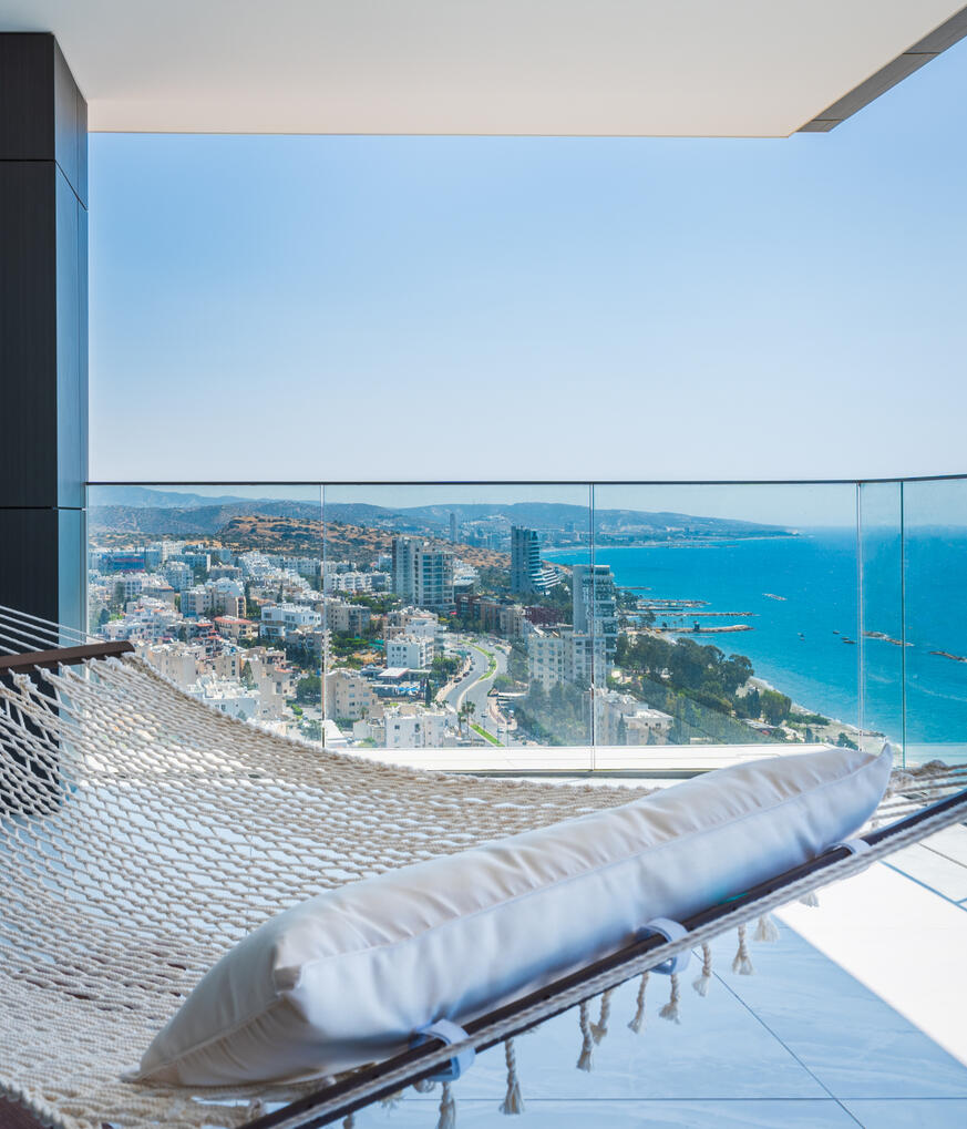 Limassol Sea View from a Balcony Real estate photography of a high-rise apartment in Limassol, Cyprus, featuring a sea view and balcony with a hammock.